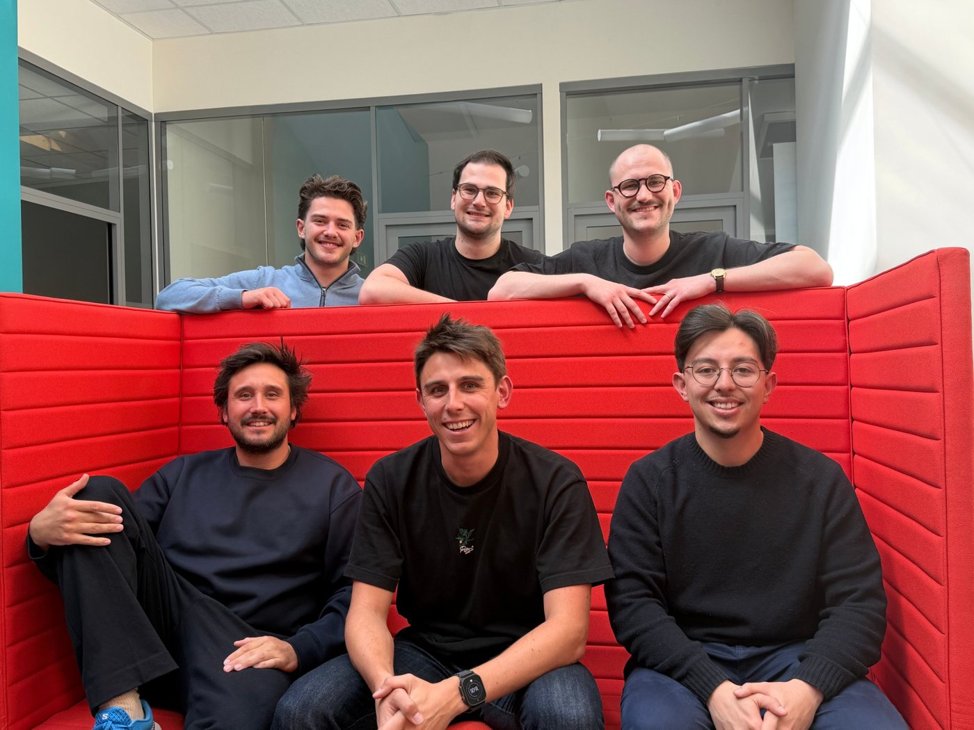Six Hoppi team members gathered around a red sofa